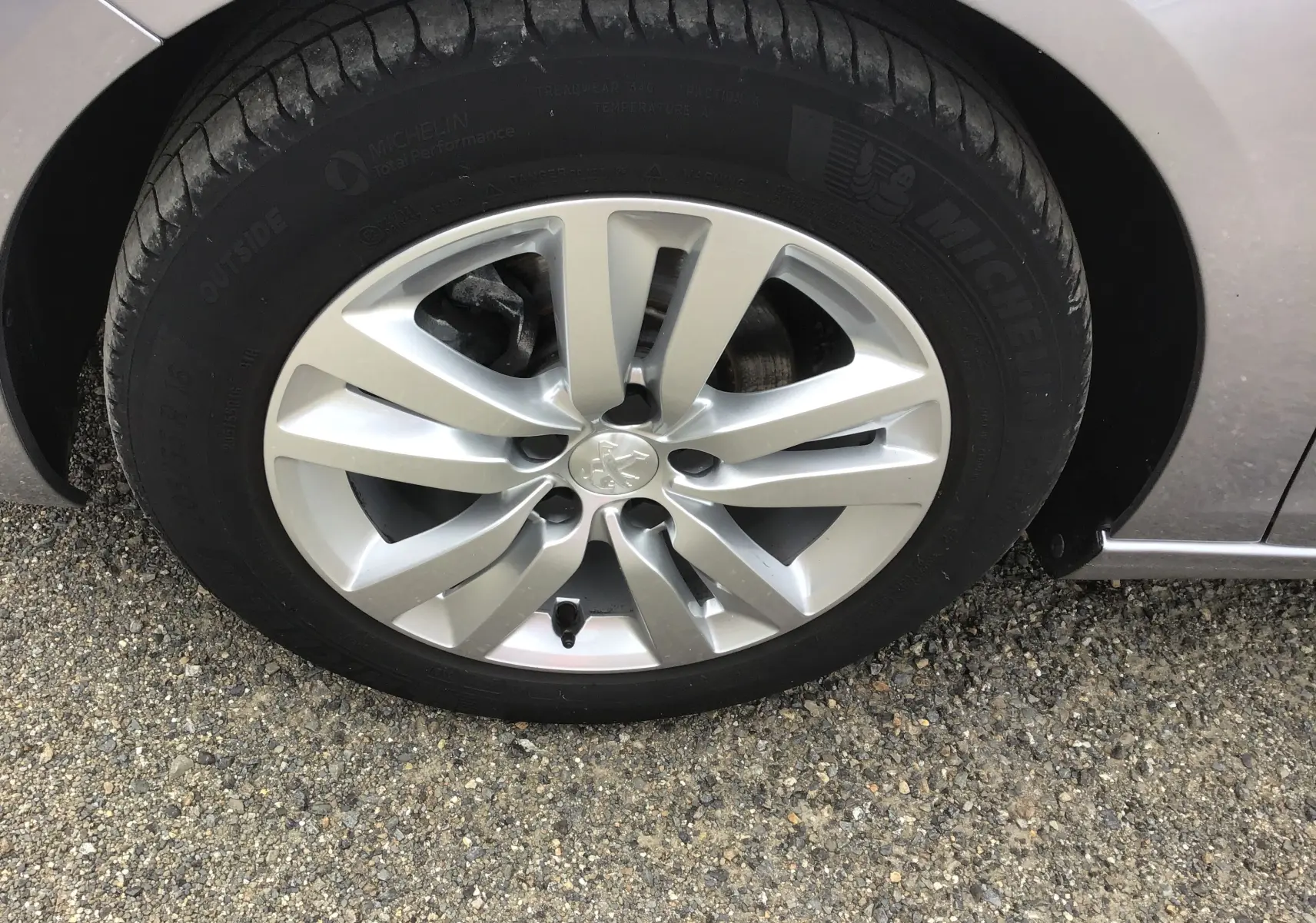Gros plan sur la roue avant gauche d’une Peugeot 308 gris Artense avec jante alliage 16 pouces et pneu Michelin.