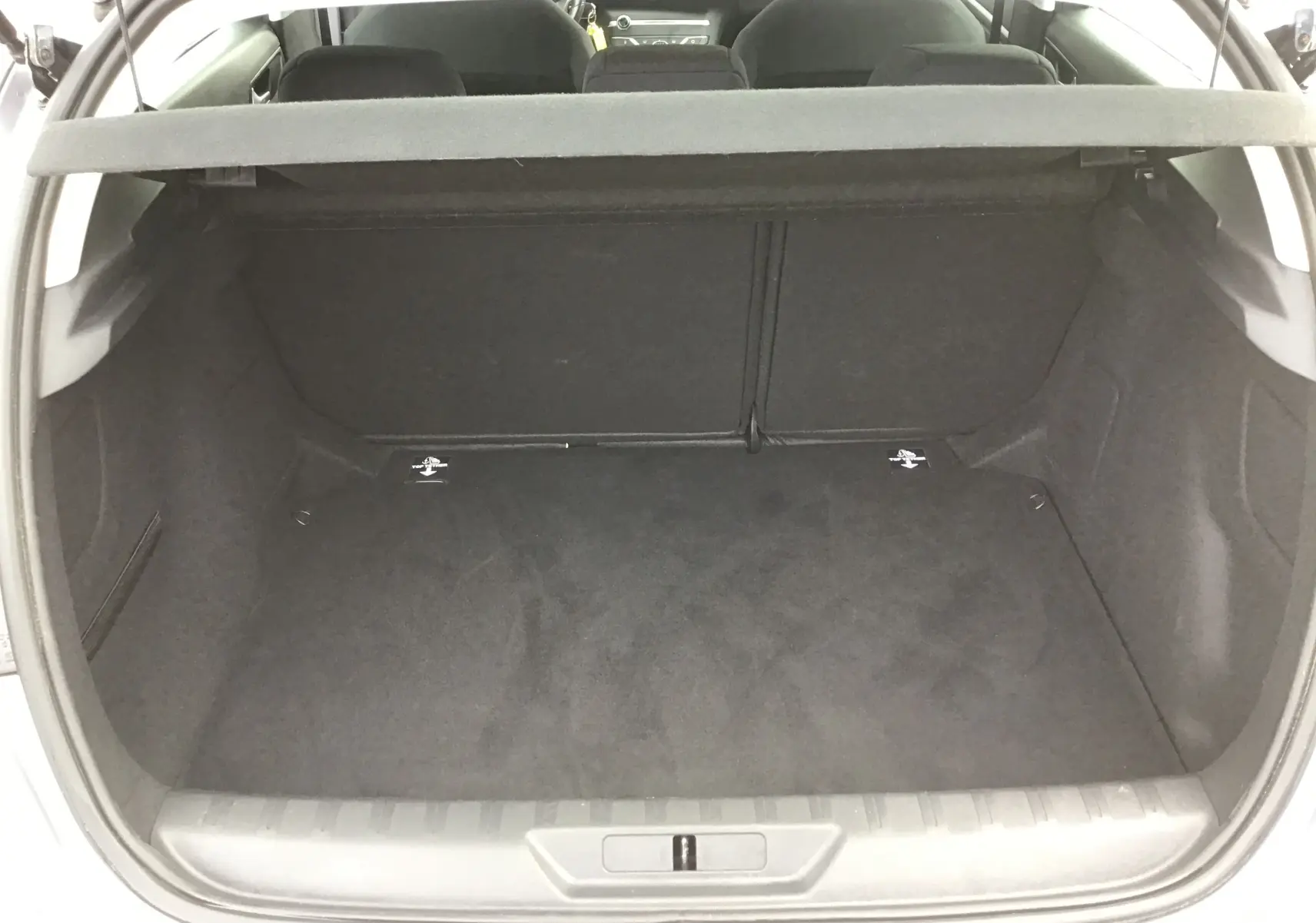 Coffre ouvert d'une Peugeot 308 gris Artense, vue arrière montrant un espace de chargement propre et spacieux.