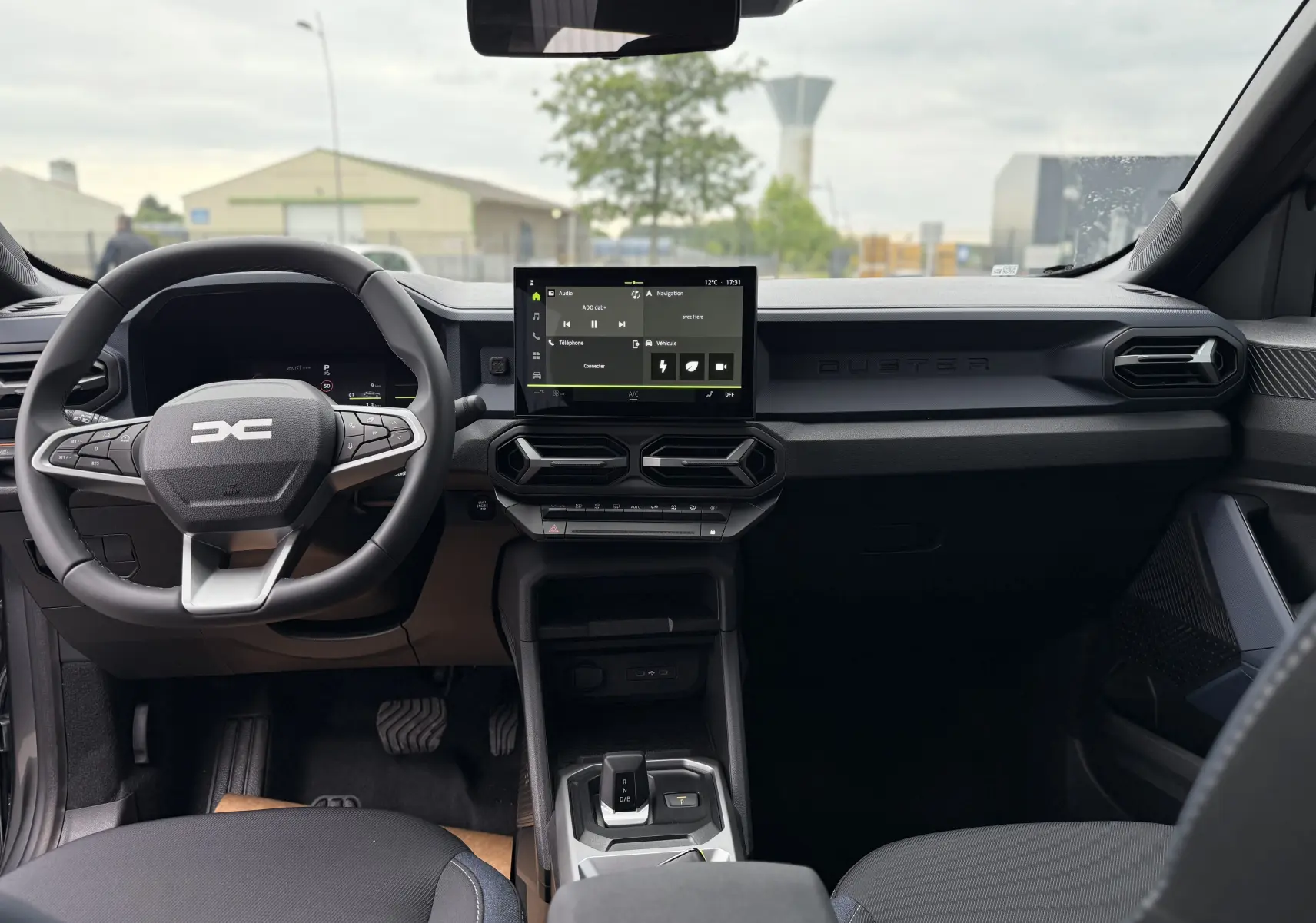 Intérieur du Dacia Duster 2025 avec tableau de bord noir, écran tactile central et volant multifonction.