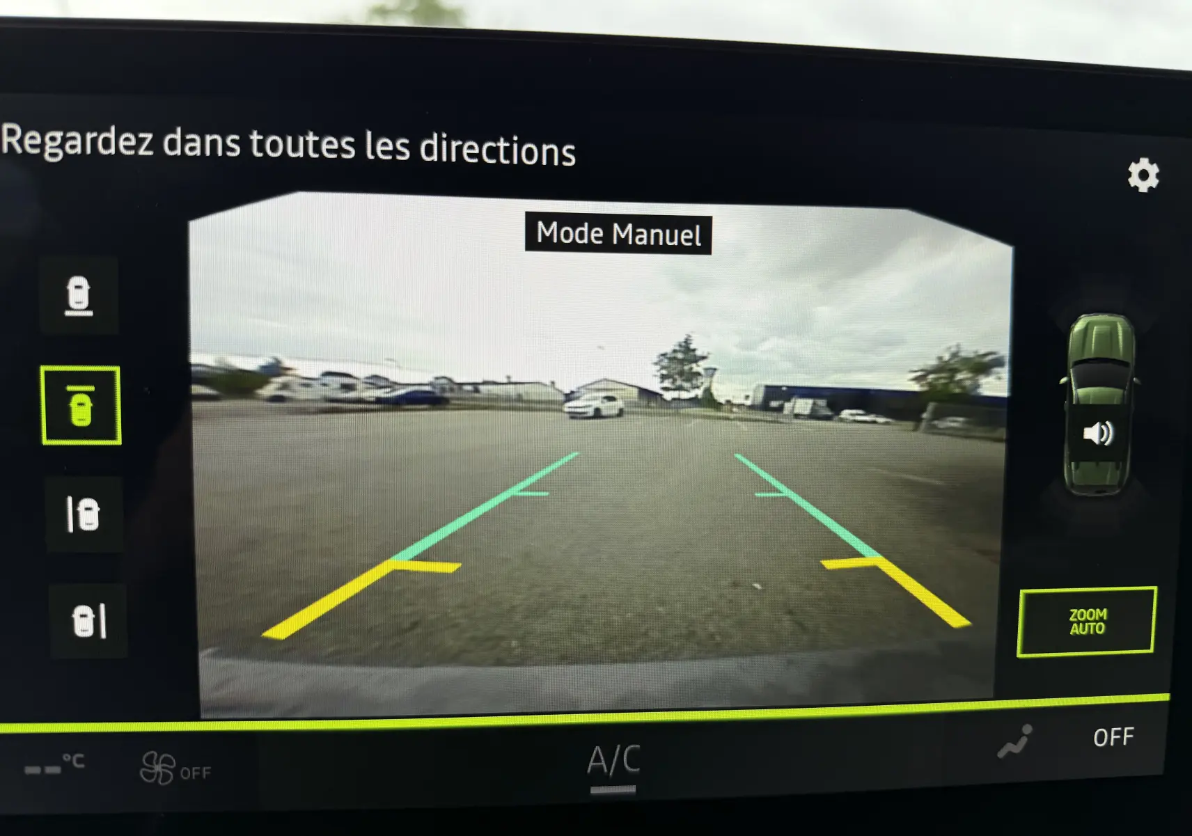 Vue écran caméra 360 du Dacia Duster gris schiste en mode manuel, affichant les lignes d'aide au stationnement arrière.