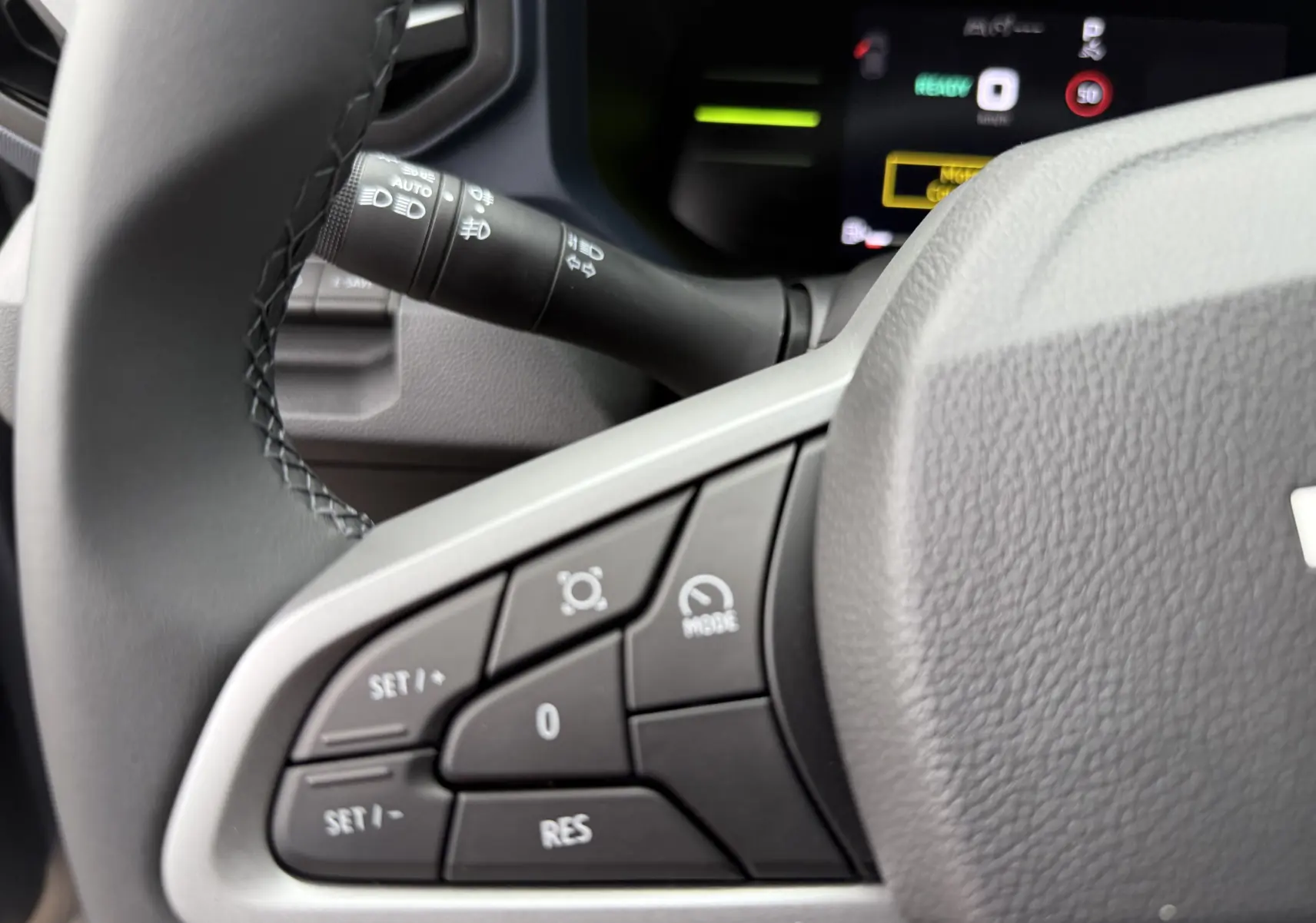 Gros plan sur les commandes au volant gris du Dacia Duster 1.6 Hybrid 140ch, avec tableau de bord numérique en arrière-plan.