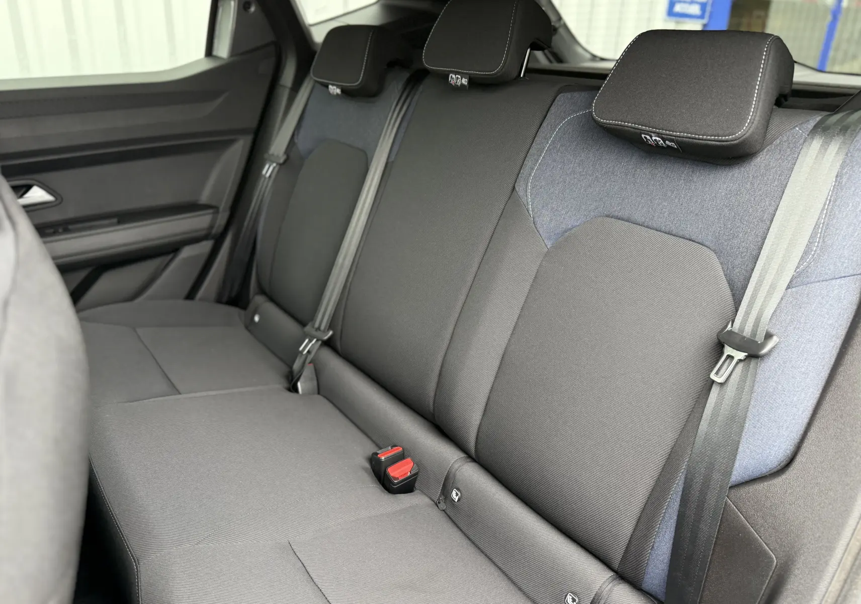 Vue intérieure sur la banquette arrière du Dacia Duster 2025, tissu noir et gris avec appuie-têtes et ceintures visibles.