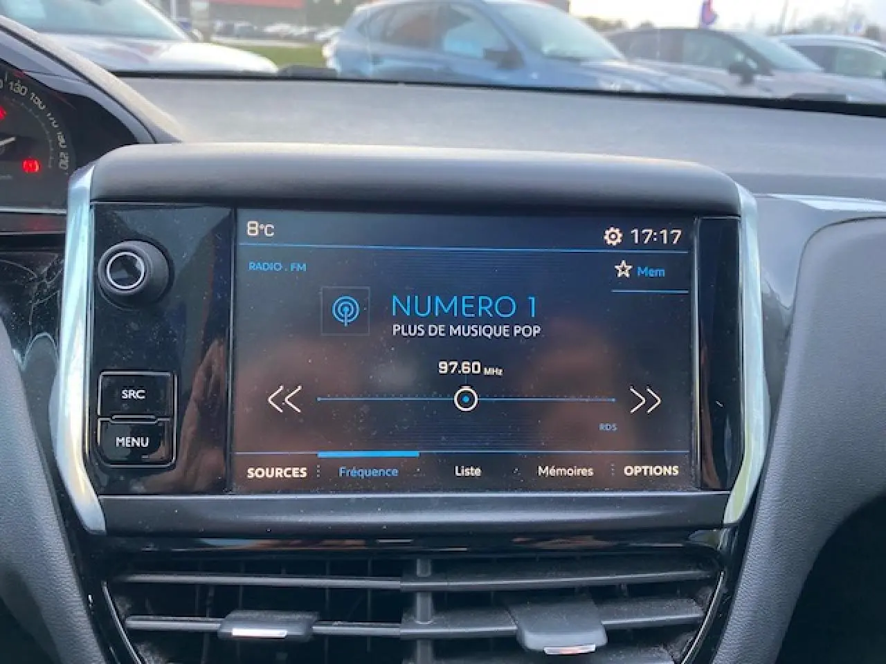 Écran tactile central affichant la radio FM dans l'habitacle d'une Peugeot 208 gris 2017 vue de face.