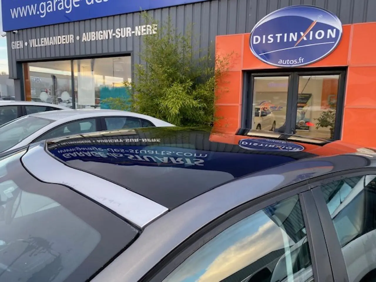 Toit panoramique en verre noir sur Peugeot 208 gris vue côté droit en extérieur devant un garage.