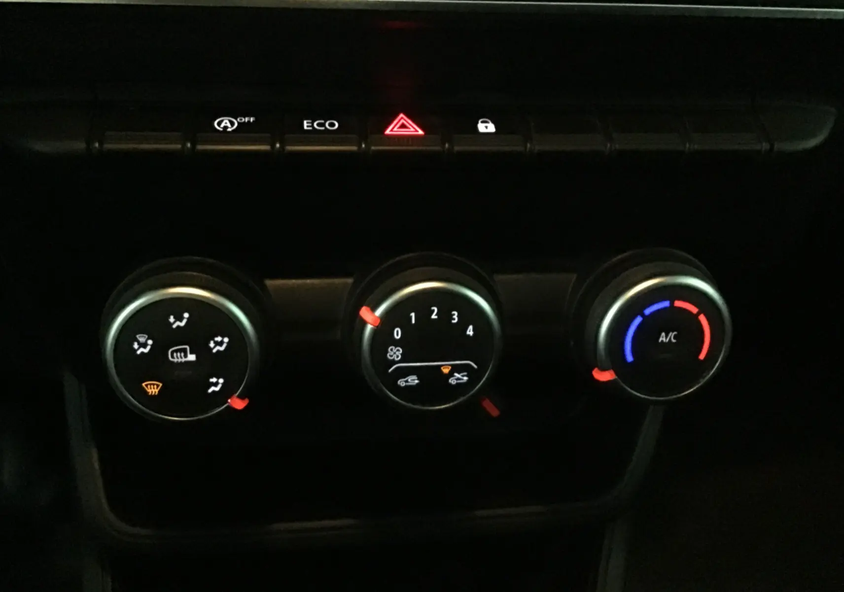 Gros plan sur les commandes de climatisation du Renault Express Van blanc 2023, avec boutons éclairés et indicateurs rouges et bleus.