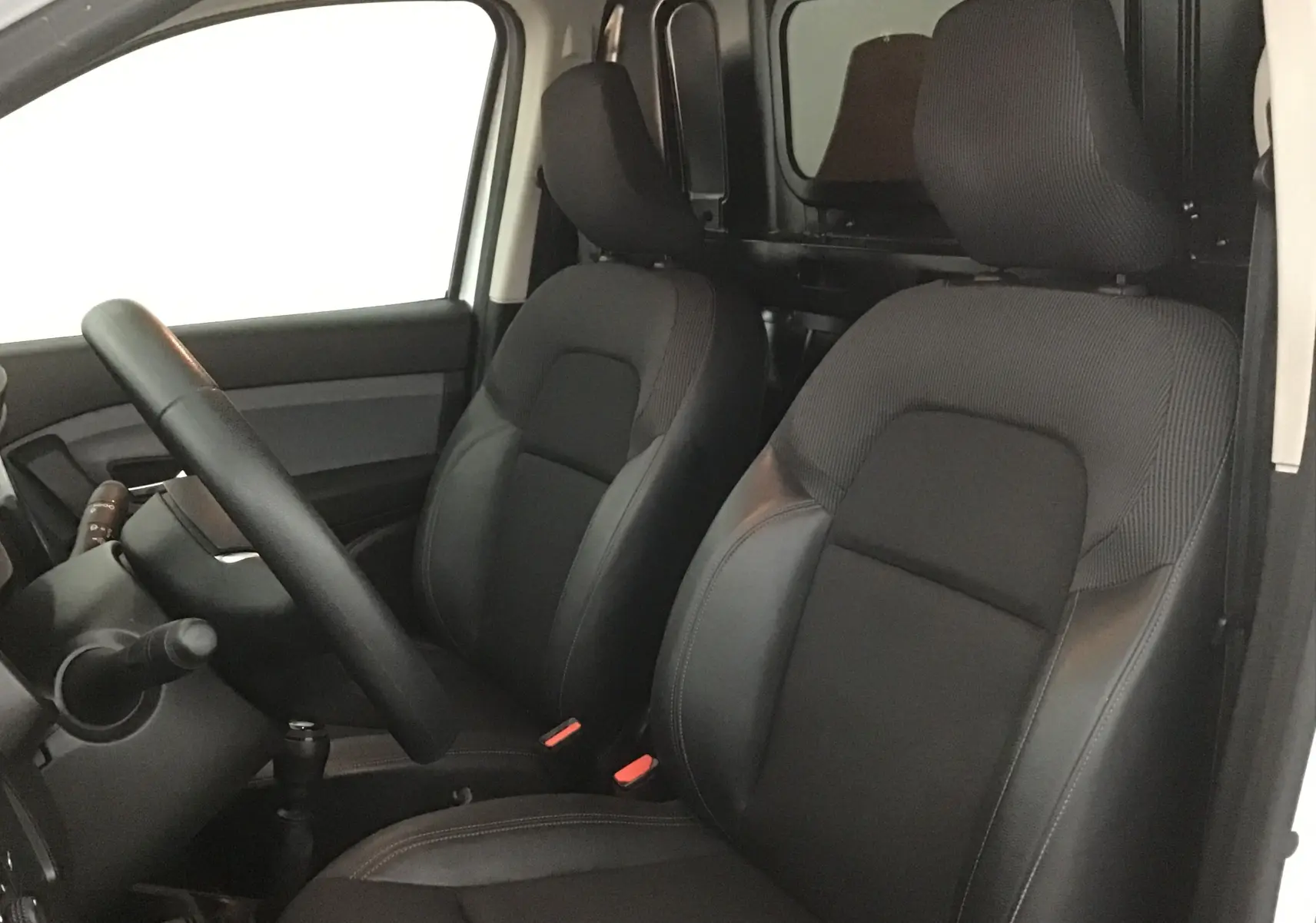 Intérieur du Renault Express Van 2023 vu côté conducteur, sièges noirs avec cloison bois derrière les sièges avant.