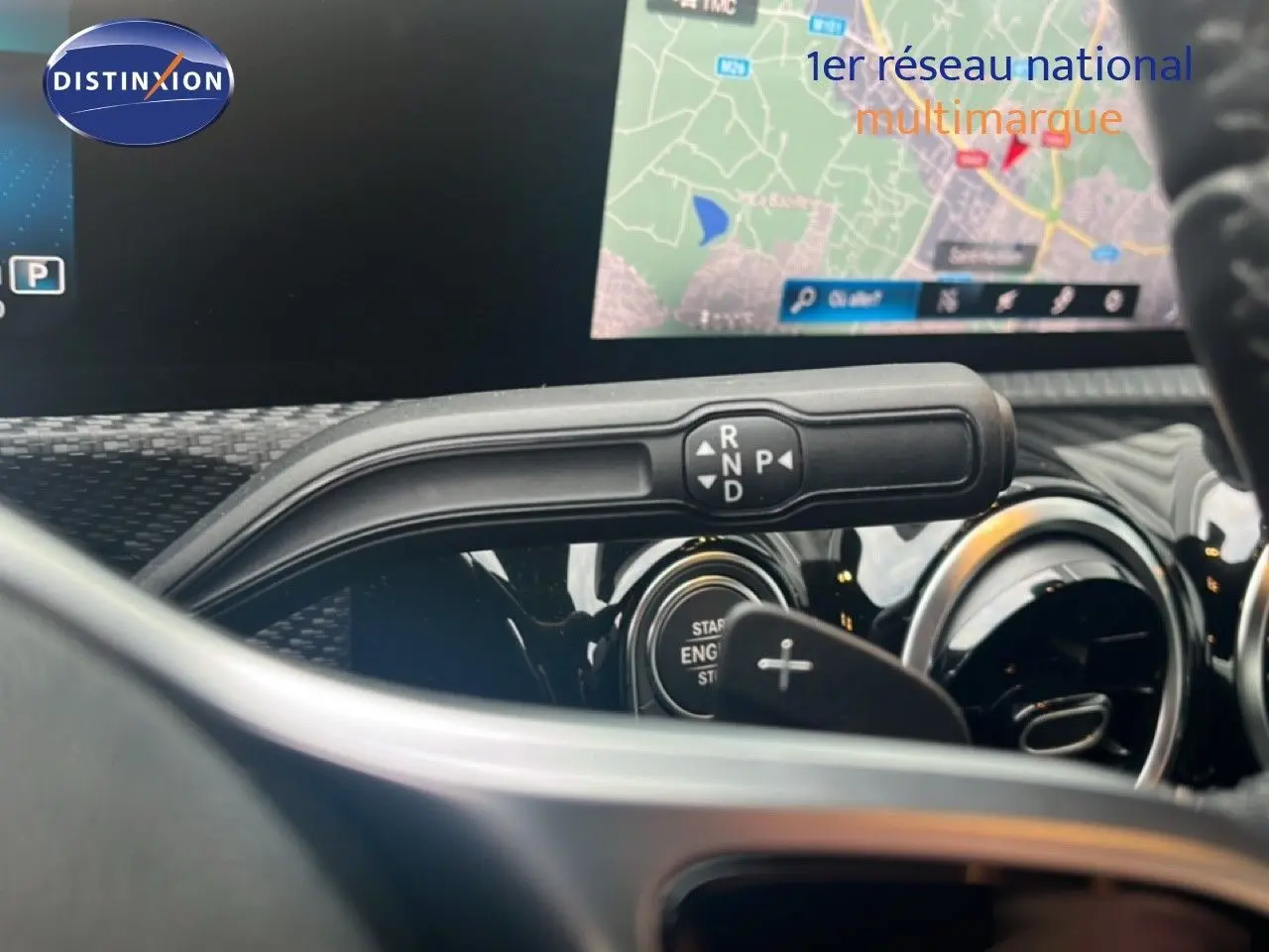 Gros plan sur la commande de boîte automatique et l'écran de navigation du tableau de bord d'une Mercedes Classe A noire.