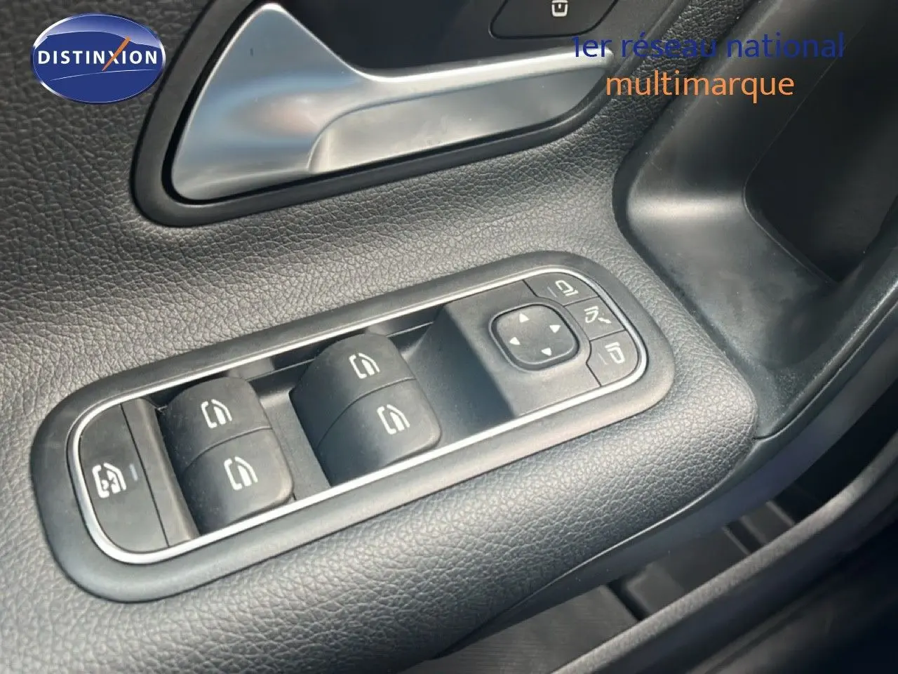 Gros plan sur les commandes des vitres côté conducteur d'une Mercedes Classe A 180 Business Line noire cosmos métal.