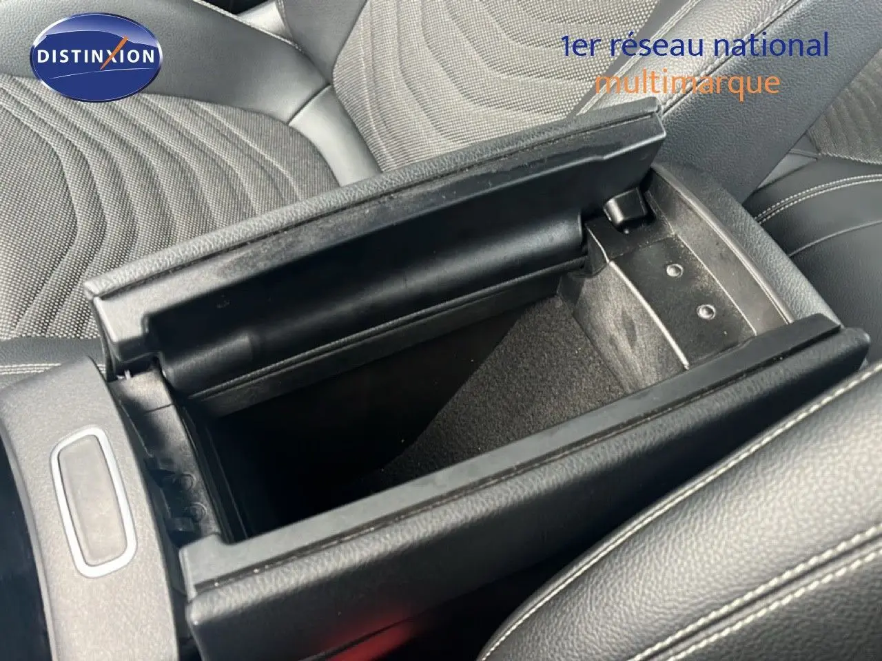 Coffre de console central ouvert montrant l’intérieur en cuir noir et tissu sur les sièges d’une Mercedes Classe A 180 Business Line 2020.