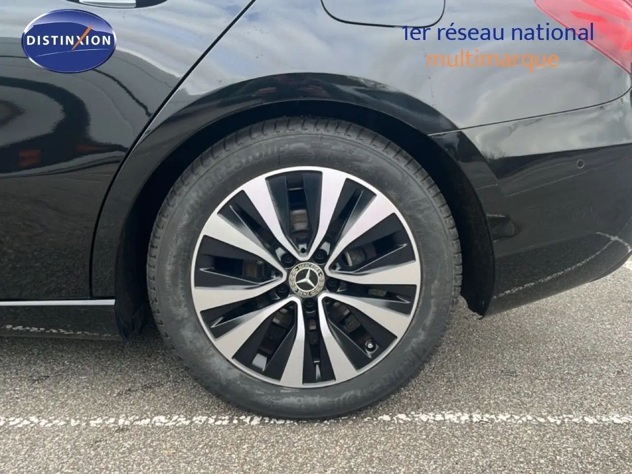 Gros plan sur la roue arrière droite d'une Mercedes Classe A 180 Business Line noire Cosmos Metal avec jante alliage bicolore.