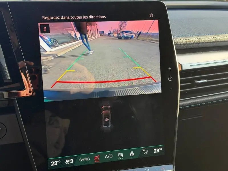 Écran intérieur montrant la caméra de recul d’un Renault Scenic blanc, vue arrière avec guidage de trajectoire coloré.
