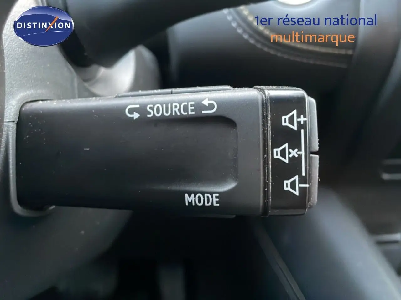 Gros plan sur la commande au volant noir du Renault Symbioz gris Casiopee Metal, avec boutons source et mode visibles.
