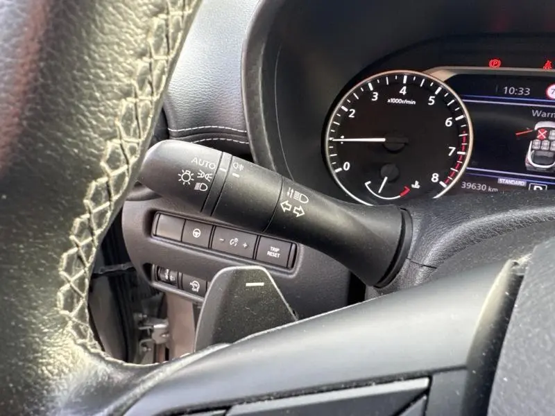 Gros plan sur le commodo gauche et le compte-tours noir du tableau de bord du Nissan Juke gris perle métallisé 2022.