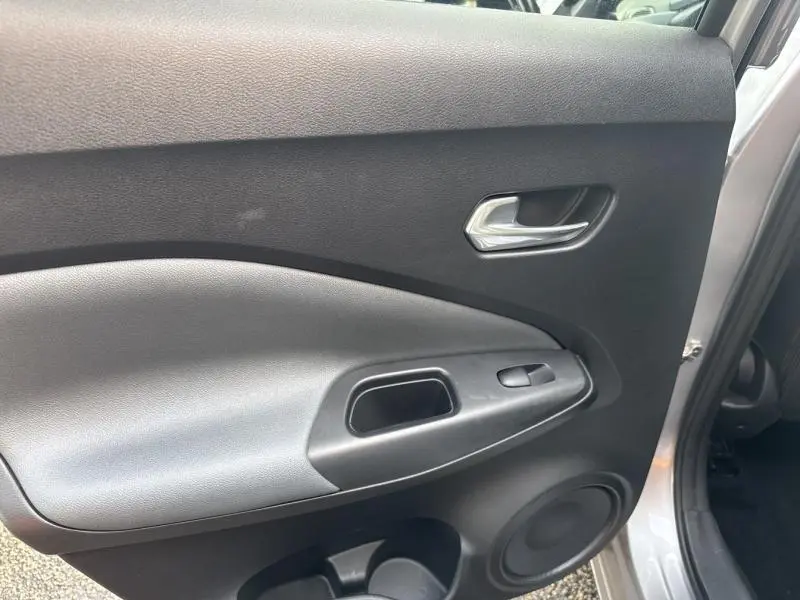 Vue intérieure de la porte arrière droite gris perle métallisé du Nissan Juke 2022 avec poignée et commande de vitre électrique.