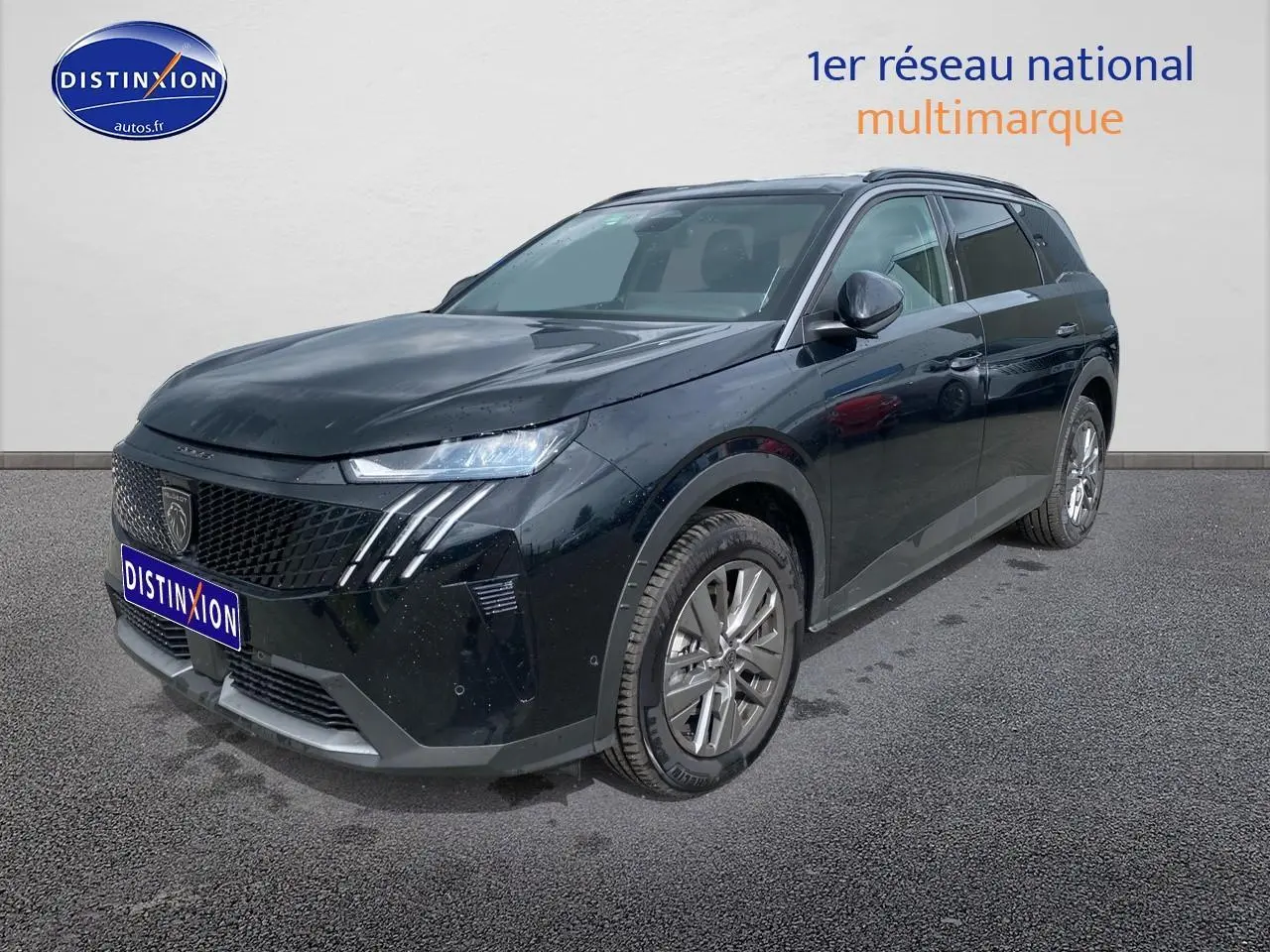 Peugeot 5008 noir en 3/4 avant droit, avec calandre distinctive et jantes alu visibles sur sol gris.
