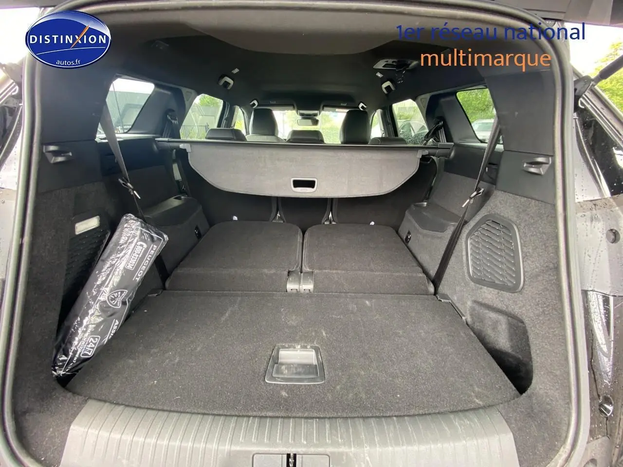 Vue arrière du coffre noir du Peugeot 5008 Hybrid 145 allure e-dcs6 avec banquette rabattue et cache-bagages déployé.
