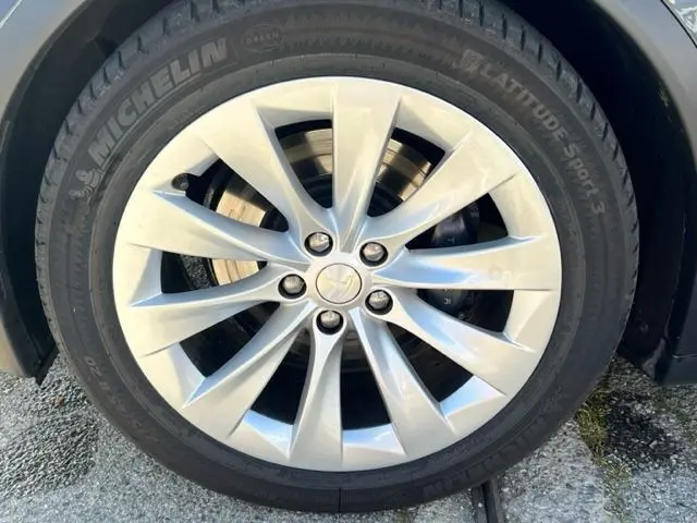 Gros plan sur la jante argentée à dix branches du Tesla Model X gris 2019, équipée de pneus Michelin Latitude Sport 3.