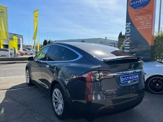 Vue 3/4 arrière droite d'une Tesla Model X gris métallisé 2019 avec porte-à-faux arrière distinctif et vitres teintées.