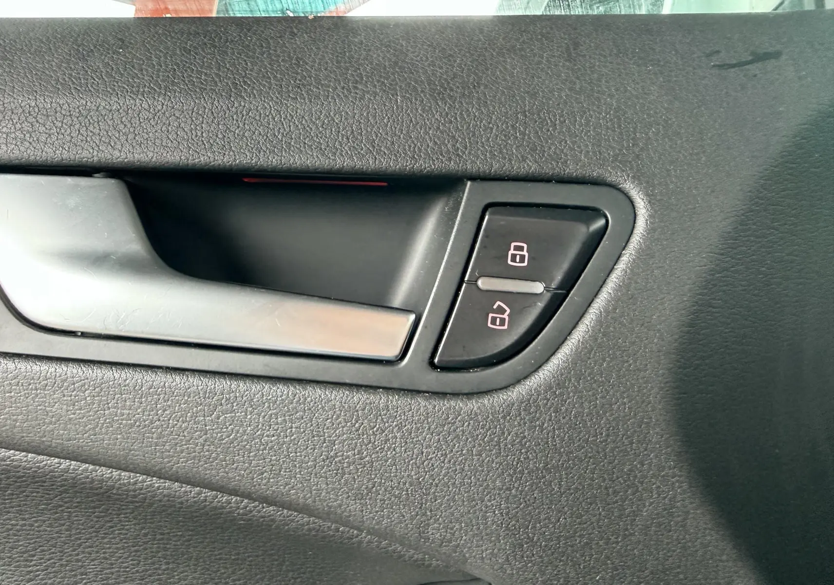 Poignée de porte intérieure côté gauche en plastique noir avec boutons de verrouillage d'une Audi A5 Sportback gris.