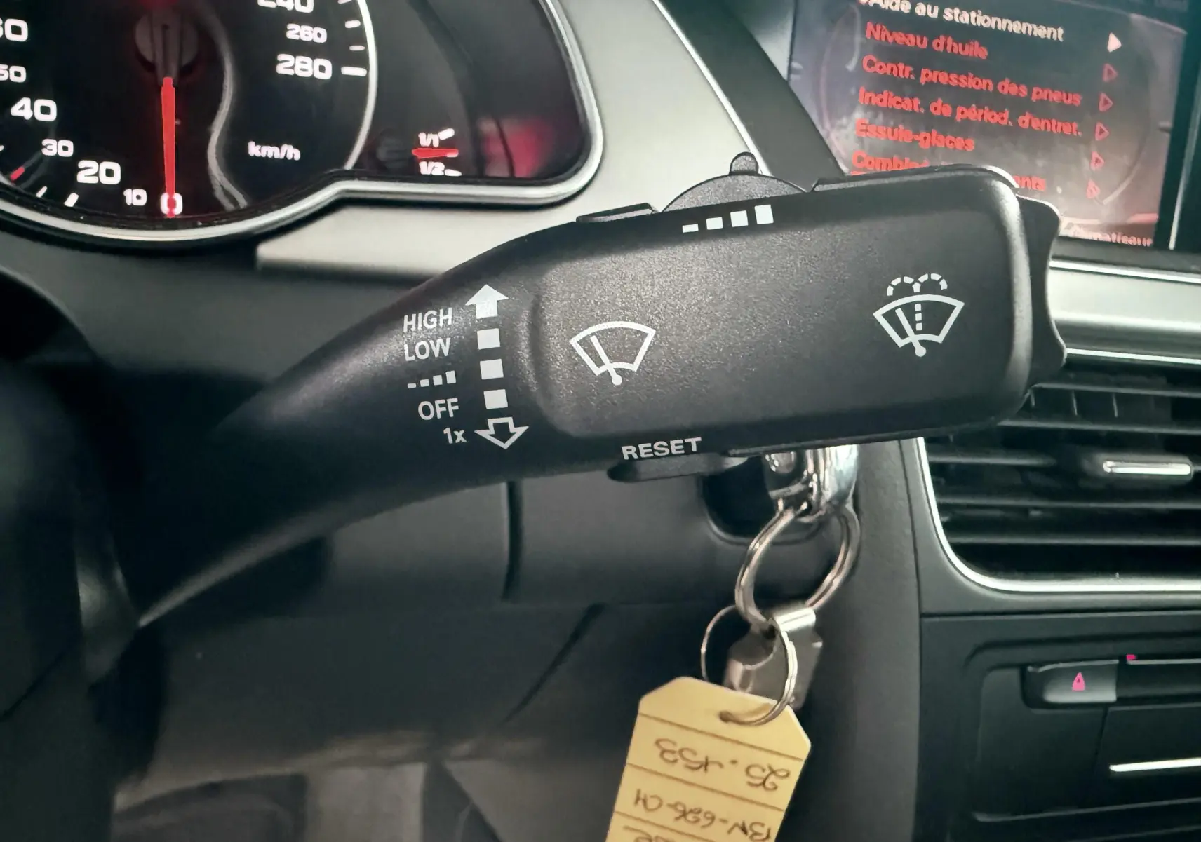 Gros plan sur le commodo d'essuie-glace de l'Audi A5 gris, avec tableau de bord et écran central en arrière-plan.