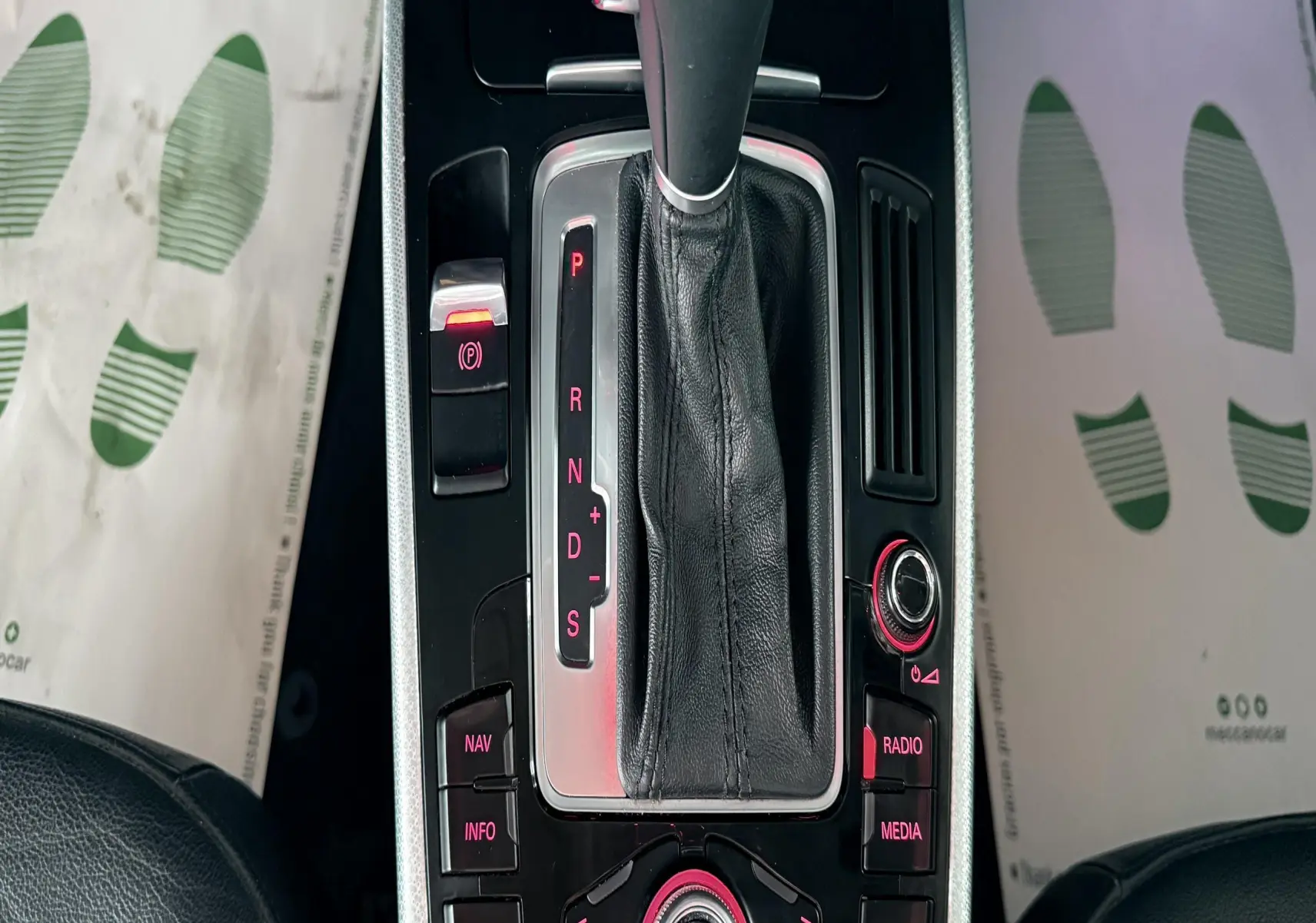 Vue rapprochée de la console centrale noire et argentée de l'Audi A5 2011 avec levier de vitesses automatique et commandes rétroéclairées rouges.