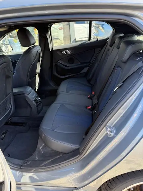 Vue intérieure côté droit montrant la banquette arrière en cuir noir de la BMW Série 1 118d Edition Sport gris foncé 2024.