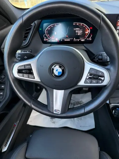 Vue rapprochée du volant cuir et alu d’une BMW Série 1 118d Edition Sport 2024 avec tableau de bord numérique.