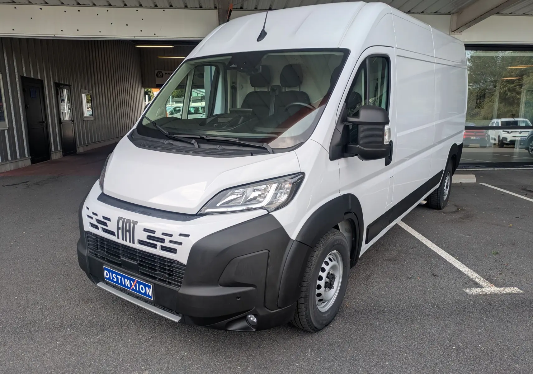 Fiat Ducato Fourgon blanc en vue 3/4 avant droit, avec pare-chocs noir et calandre distinctive, stationné en extérieur.