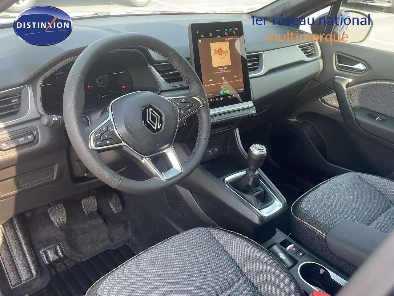 Vue intérieure côté conducteur du Renault Captur 2025, tableau de bord moderne avec écran tactile vertical et levier de vitesse manuel.