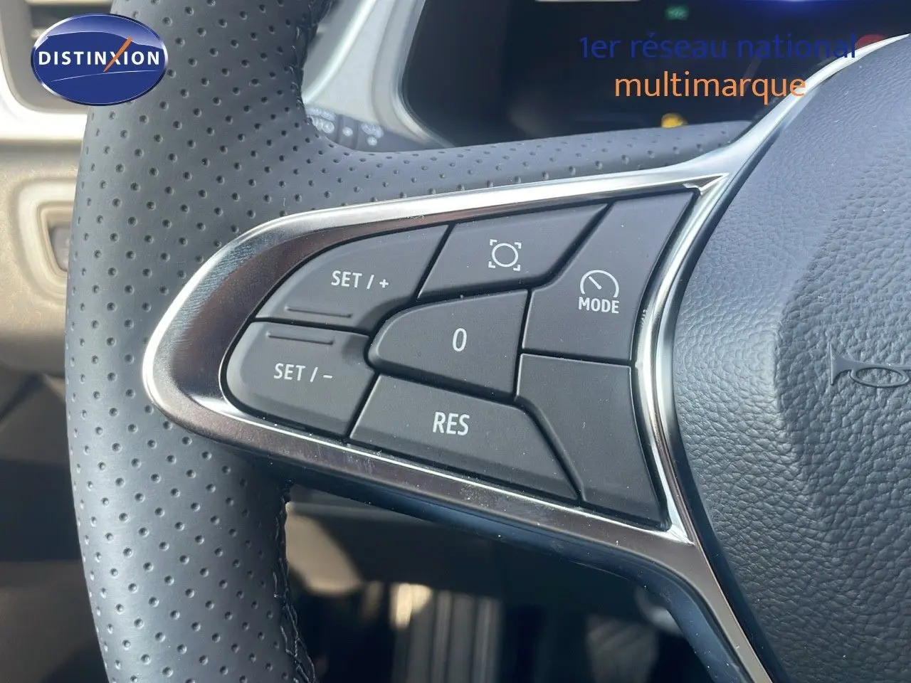 Gros plan sur les commandes du volant en cuir perforé du Renault Captur bleu Iron Metal, version mild hybrid 2025.
