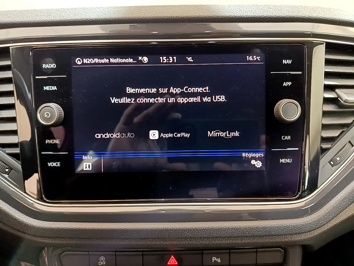 Écran tactile central du tableau de bord du Volkswagen T-Roc blanc, affichant App-Connect et options de connectivité.