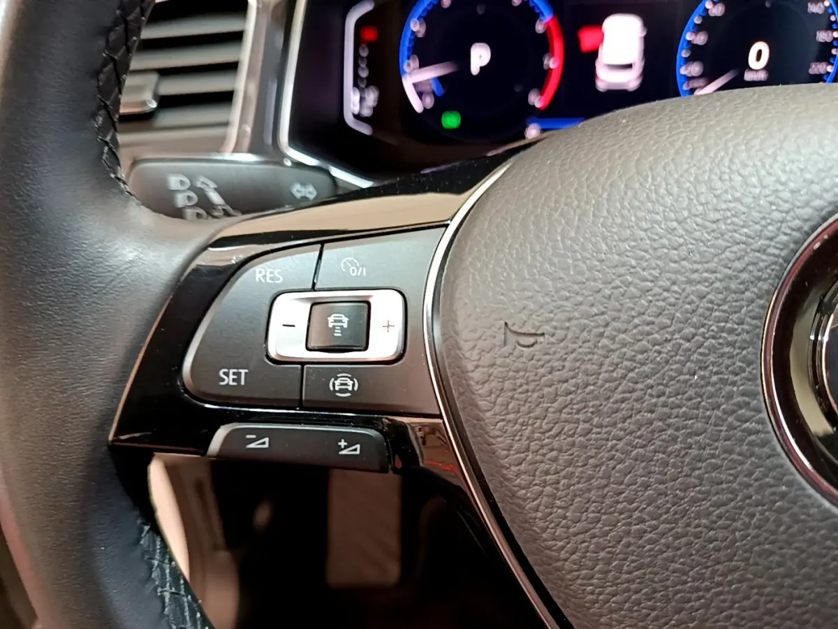 Gros plan sur le volant cuir du Volkswagen T-Roc blanc 2020, avec commandes de régulateur adaptatif visibles.