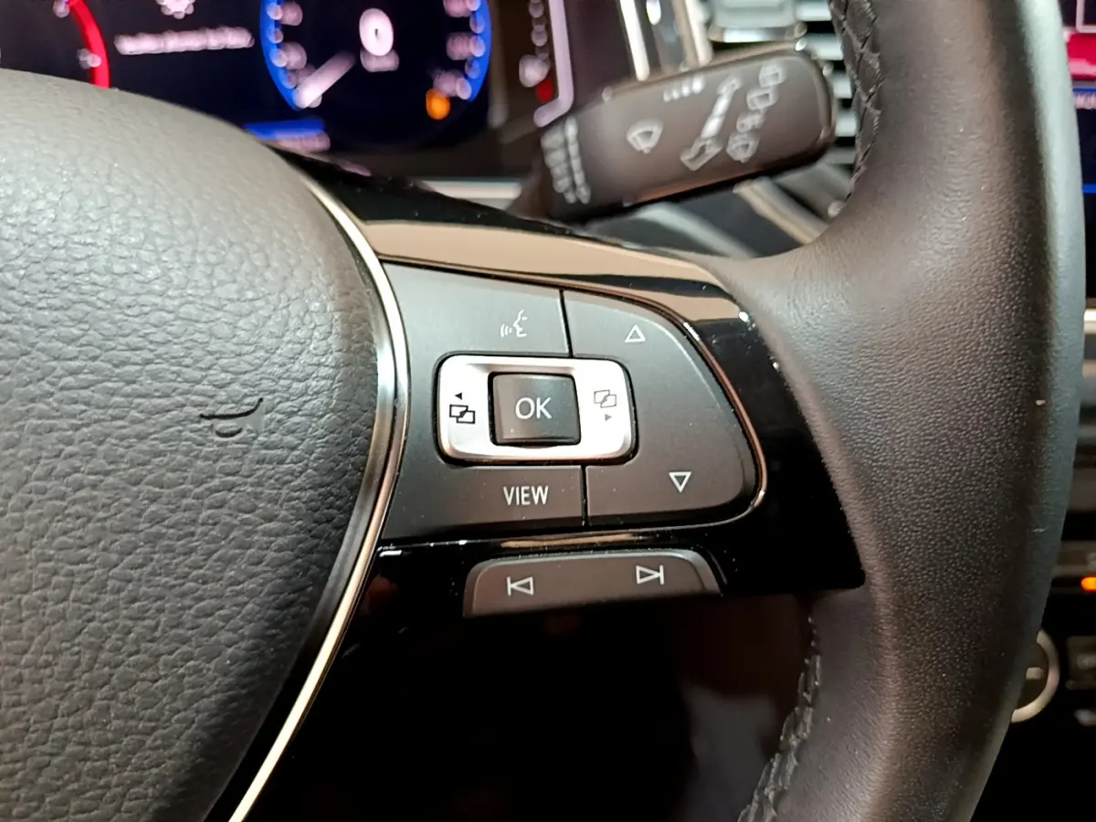 Gros plan sur les commandes à droite du volant cuir du Volkswagen T-Roc blanc, avec affichage numérique en arrière-plan.