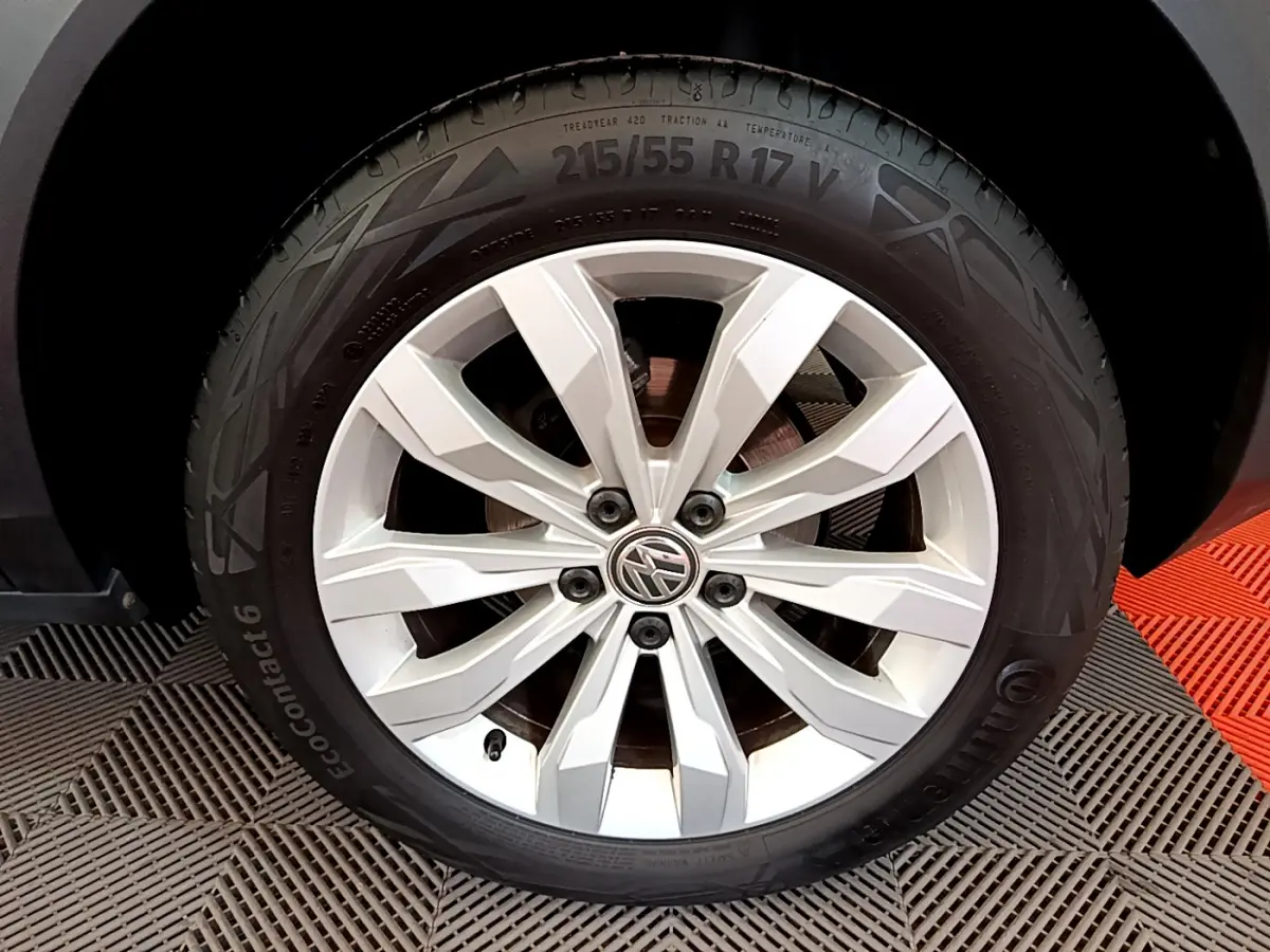 Gros plan sur la roue avant droite d'un Volkswagen T-Roc blanc avec jante alliage à dix branches.