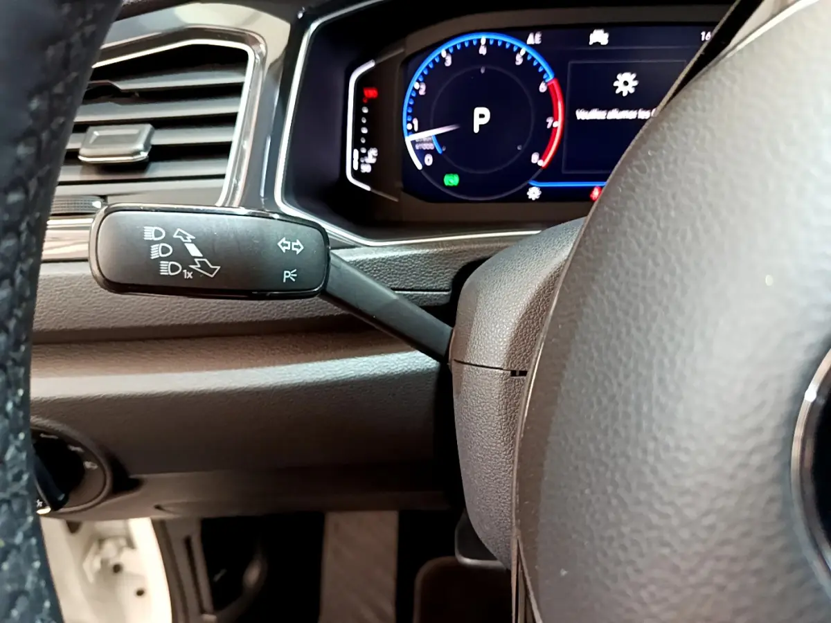 Gros plan sur le volant et le compteur digital du Volkswagen T-Roc 1.5 TSI blanc, affichant le mode parking.