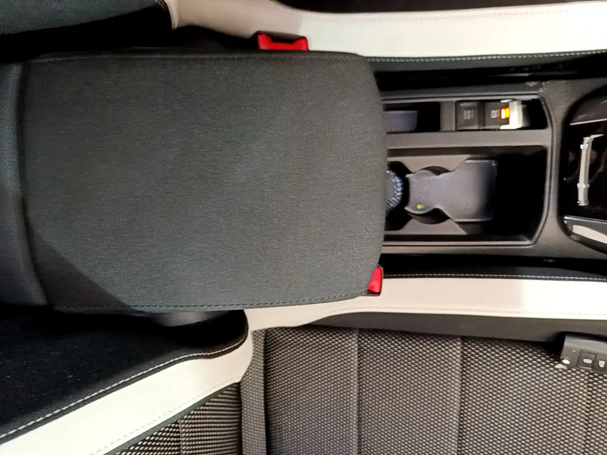 Vue plongeante sur l'accoudoir central et console noire avec porte-gobelets du Volkswagen T-Roc 1.5 TSI blanc 2020.