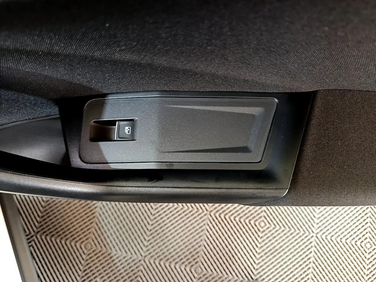 Gros plan sur le bouton de lève-vitre électrique côté conducteur du Volkswagen T-Roc blanc, intérieur noir.