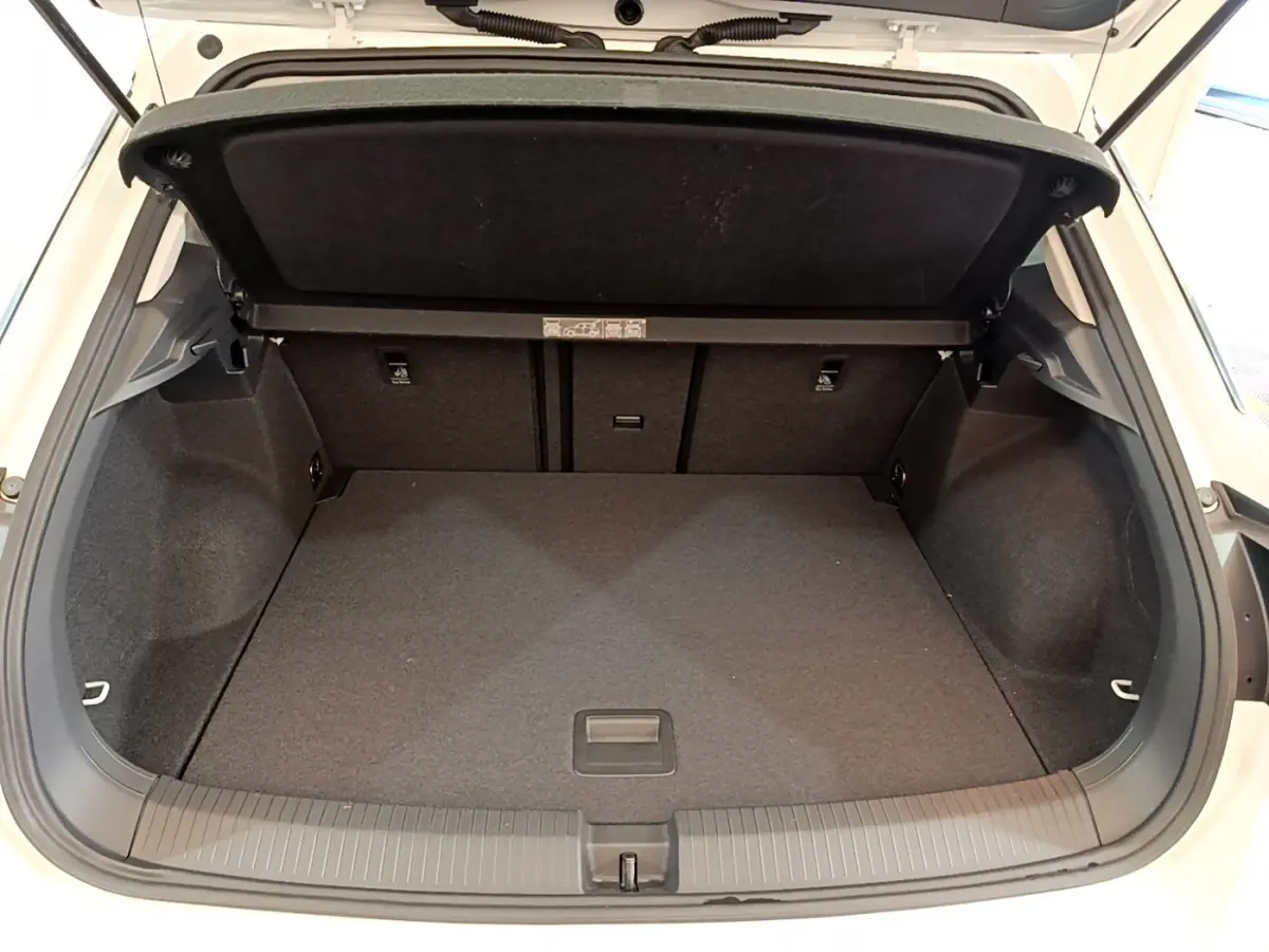 Coffre ouvert du Volkswagen T-Roc blanc, vue arrière montrant l'espace de chargement vide et la tablette de couverture.