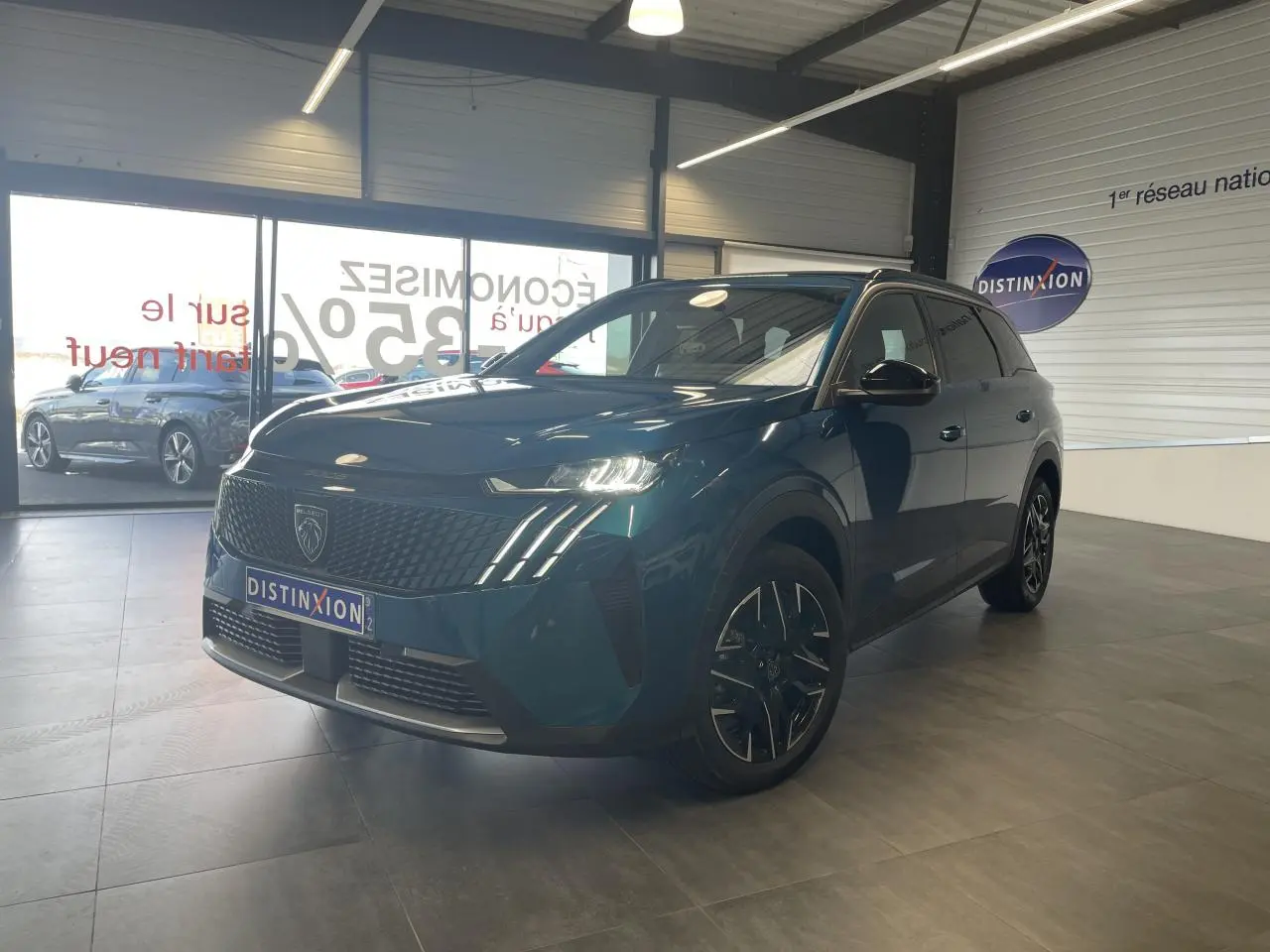 Peugeot 5008 Bleu Obsession en 3/4 avant droit, avec calandre noire et jantes alliage 19 pouces dans un showroom.