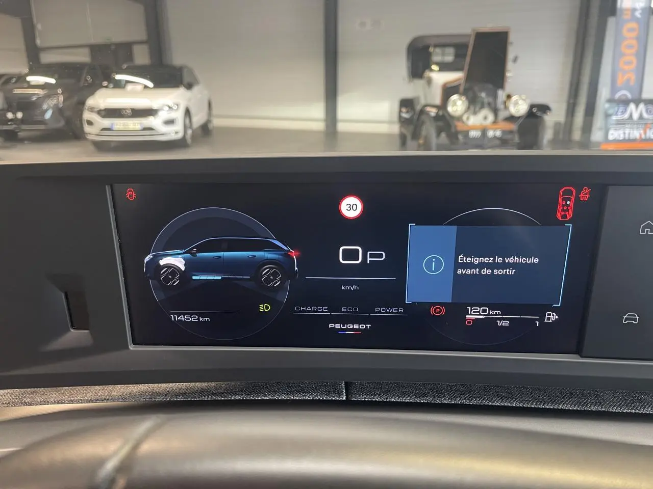 Écran numérique du tableau de bord du Peugeot 5008 Bleu Obsession affichant la silhouette du véhicule et alertes de sécurité.