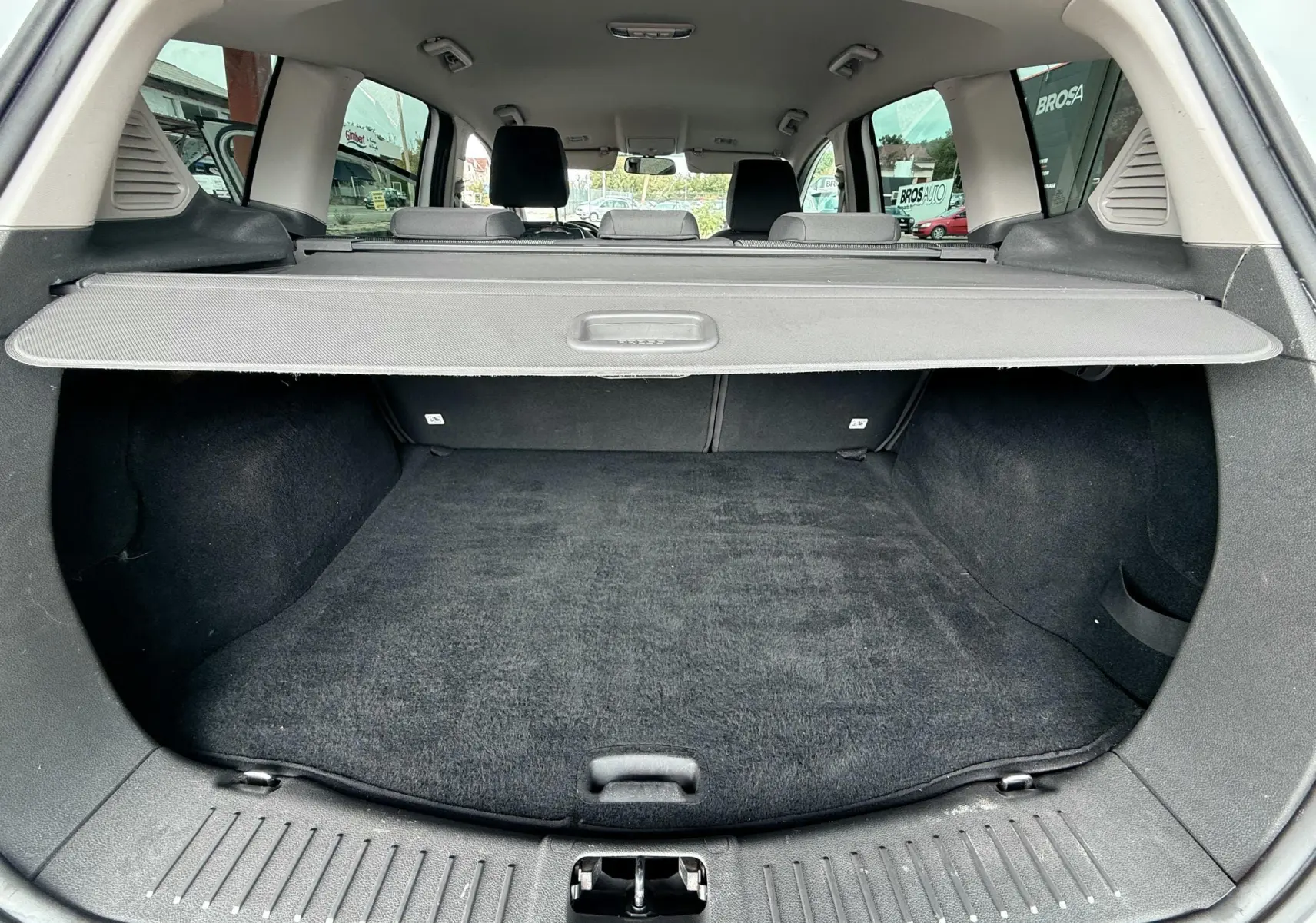 Vue du coffre arrière ouvert du Ford Kuga blanc de 2012, montrant l'espace de chargement avec cache-bagages déployé.