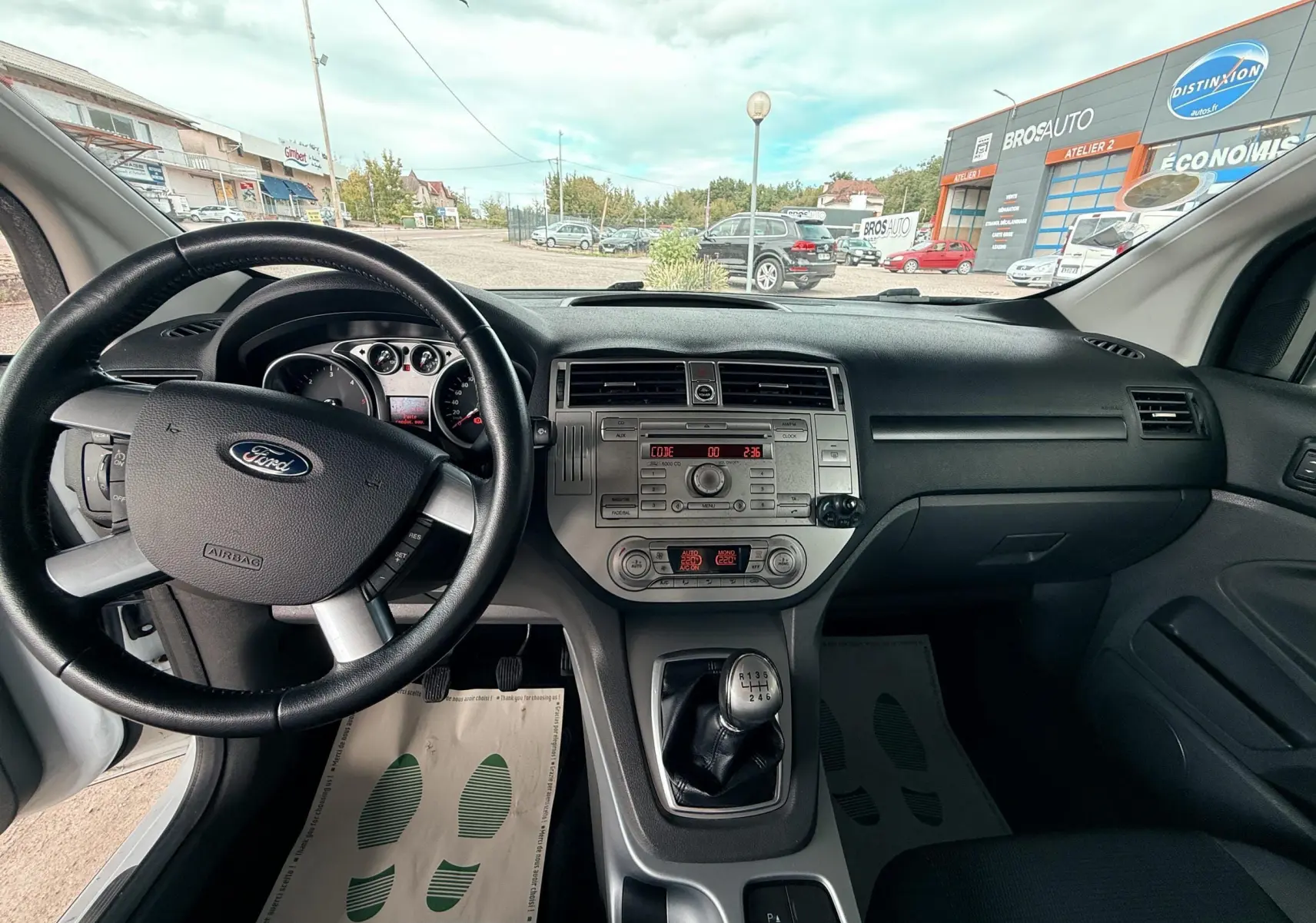 Vue intérieure avant du Ford Kuga 2012 avec tableau de bord noir, volant cuir et levier de vitesse manuel.