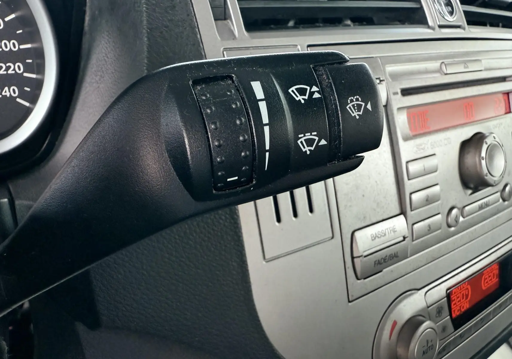 Gros plan sur la manette de commande d'essuie-glace à gauche du tableau de bord gris du Ford Kuga blanc 2012.