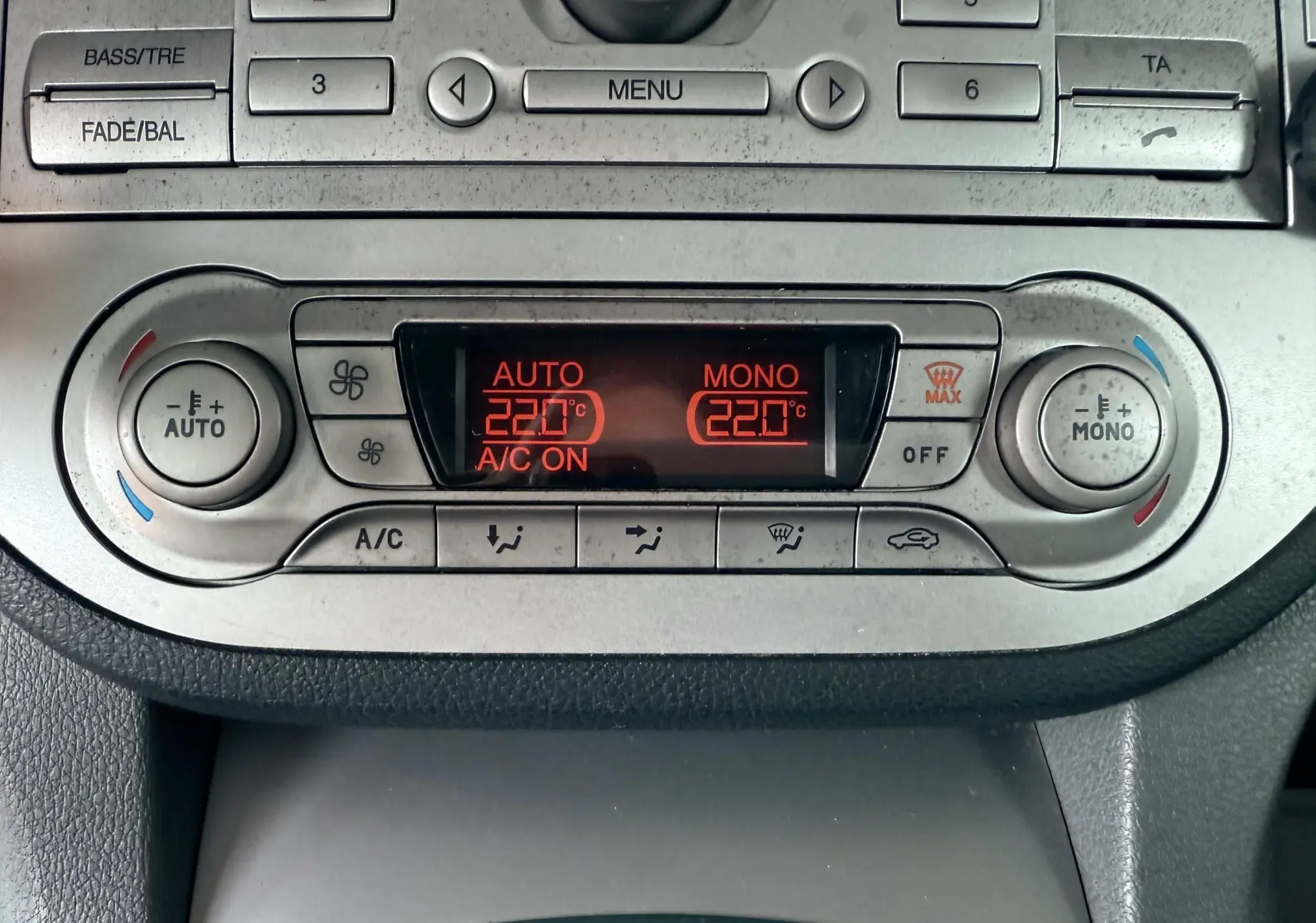 Vue rapprochée de la console centrale du Ford Kuga 2012 montrant la climatisation automatique à 22°C et les commandes radio.