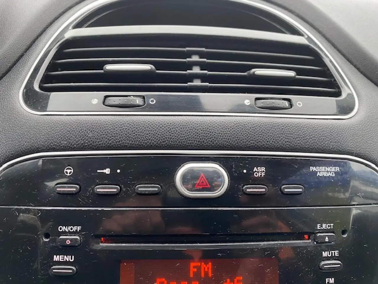 Tableau de bord de Fiat Grande Punto 2015 en gros plan, avec commandes radio et ventilation visibles.