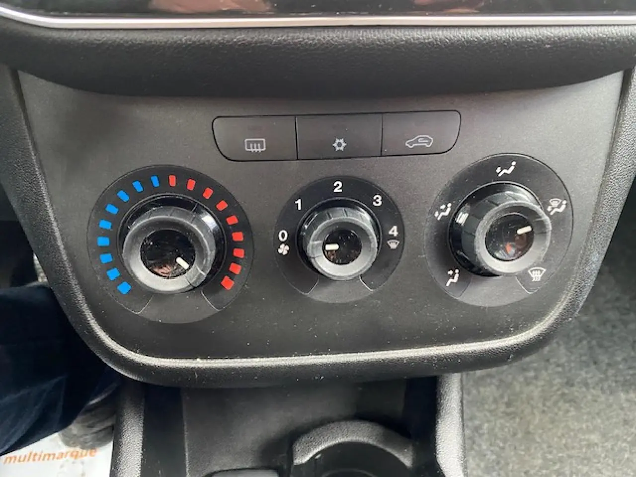 Tableau de commande de climatisation manuel noir d'une Fiat Grande Punto gris, avec réglages température, ventilation et air.