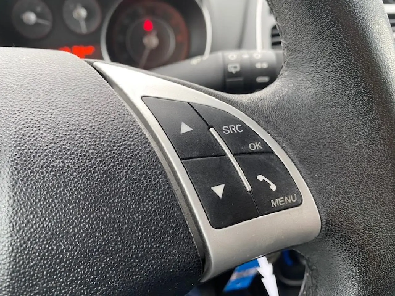 Gros plan sur les commandes au volant de la Fiat Grande Punto gris métallisé, avec boutons SRC, OK et menu visibles.