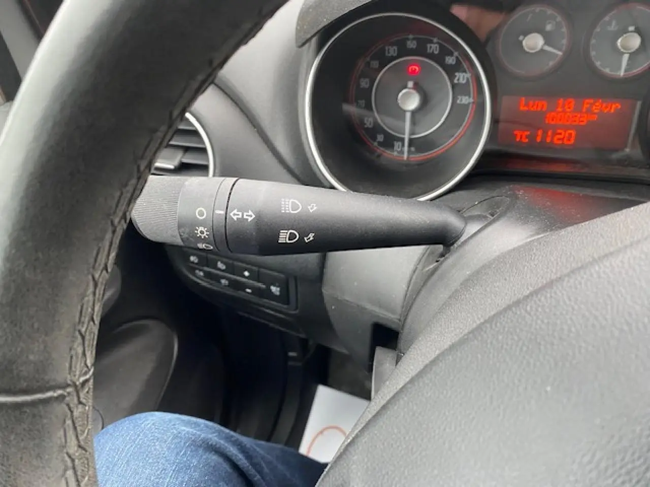 Gros plan sur le commodo des feux et le tableau de bord du Fiat Grande Punto gris, avec compteur et affichage digital rouge.