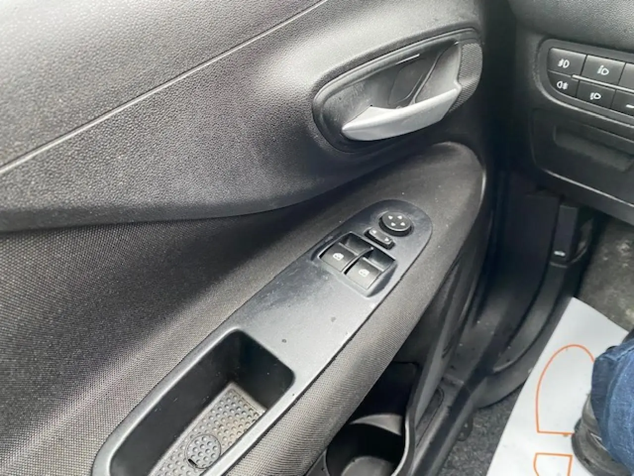 Gros plan sur la porte côté conducteur de la Fiat Grande Punto gris, montrant les commandes des vitres électriques et la poignée intérieure.