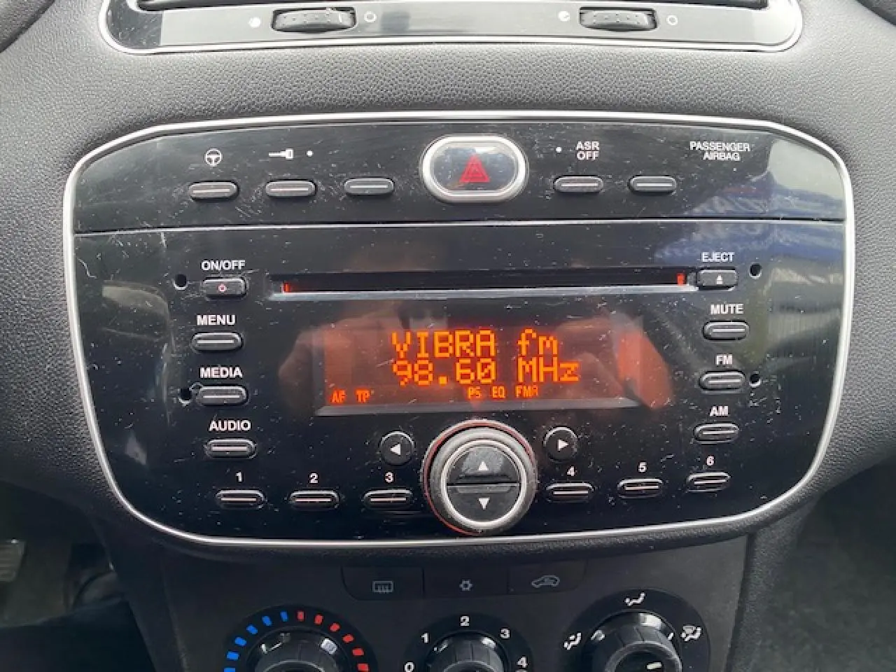 Gros plan sur la radio CD MP3 intégrée du tableau de bord d'une Fiat Grande Punto gris métallisé, affichant la station VIBRA fm.